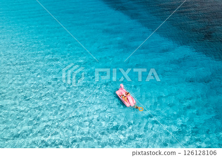 Aerial view of Inflatable pink flamingo with people on blue sea 126128106