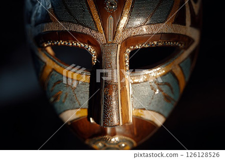 Illuminated cyber ritual mask with african tribal patterns displayed in a museum 126128526
