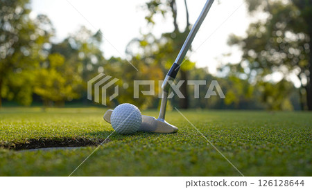 Golf clubs and golf balls on a green lawn in a beautiful golf course with morning sunshine. Golf clubs and golf balls on a green lawn in a beautiful golf course with morning sunshine. 126128644