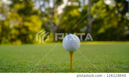 Golf ball on tee in a beautiful golf course with morning sunshine. Golf ball on tee in a beautiful golf course with morning sunshine. 126128648