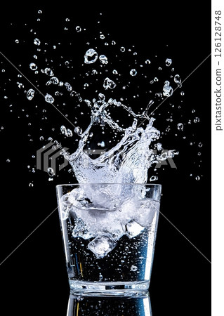 Refreshing splashing mineral water with ice cubes on black background 126128748