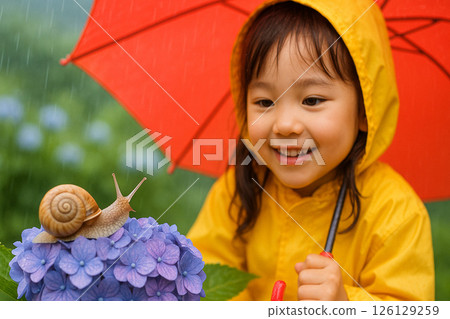 A girl smiles at a snail on a hydrangea during the rainy season 126129259
