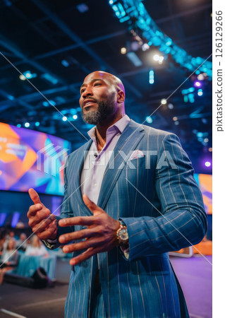 Charismatic male speaker presenting on stage during dynamic business event 126129266