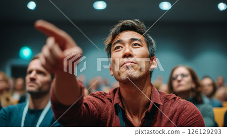 Young man pointing with interest during Q&A at seminar event 126129293