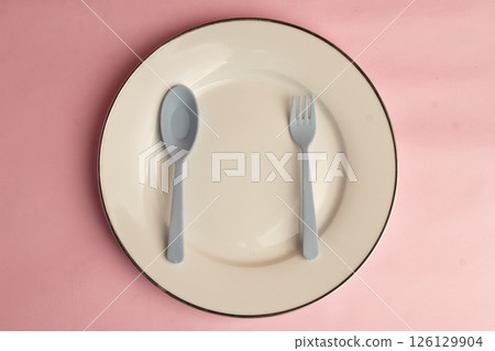 Minimalist Cutlery Arrangement on Pink Canvas, Gray Plastic Spoon and Fork Plate Arrangement, Top View studio shot 126129904