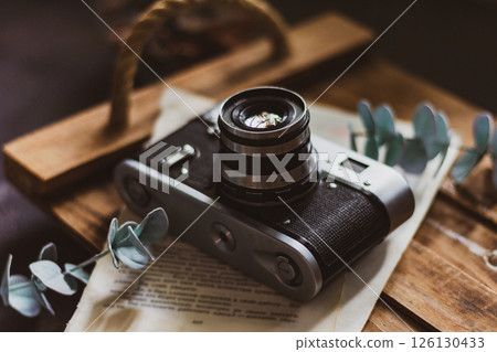 Retro camera on old book and eucalyptus branch on wooden background, flat lay. Vintage style. Retro camera on old book and eucalyptus branch on wooden background, flat lay. Vintage style. 126130433