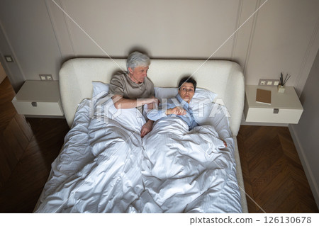 Crisis in long term relationship, mature couple arguing on bed, woman pulling hand in frustration 126130678