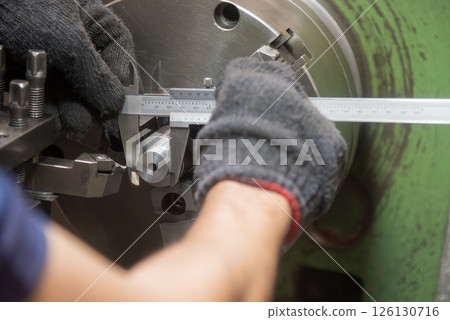 Close up scene the machine operator measuring diameter of turning parts by Vernier caliper. 126130716