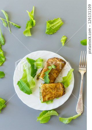 Omelette roll with greens and fresh arugula on a plate 126131109