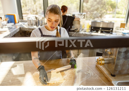 A skilled and experienced baker is diligently preparing fresh dough in a modern bakery setting 126131211