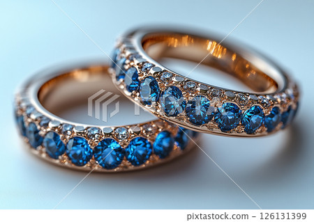 Luxurious pair of wedding rings with blue stones on a white background. Rococo-Renaissance style. 126131399