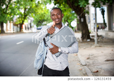 portrait of young man with laptop, smiling. 126131459