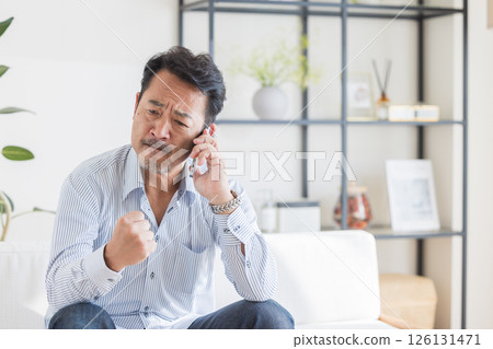 一個在客廳裡使用智能手機的人 一個在客廳裡使用智能手機的人 126131471