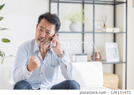 一個在客廳裡使用智能手機的人 126131472