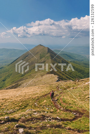 Woman Hikes on Mountain Path with Travel Backpack Woman Hikes on Mountain Path with Travel Backpack 126132599