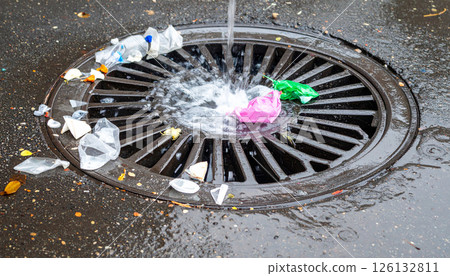 Street drain grate overflowing with plastic waste 126132811