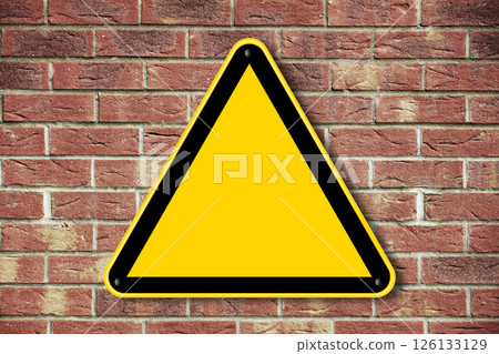 Blank yellow caution triangle sign on a brick wall 126133129