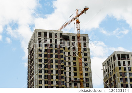 New skyscraper under construction with construction crane against cloudy sky. Highrise Building Site. New skyscraper under construction with construction crane against cloudy sky. Highrise Building Site. 126133154