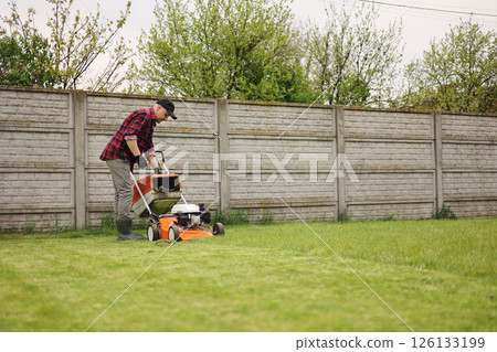 man in casual clothes holds bag with cut grass of lawn mower after mowing lawn with at own backyard. Husband takes care of garden. Modern gasoline garden equipment. Landscaping work at home man in casual clothes holds bag with cut grass of lawn mower after mowing lawn with at own backyard. Husband takes care of garden. Modern gasoline garden equipment. Landscaping work at home 126133199