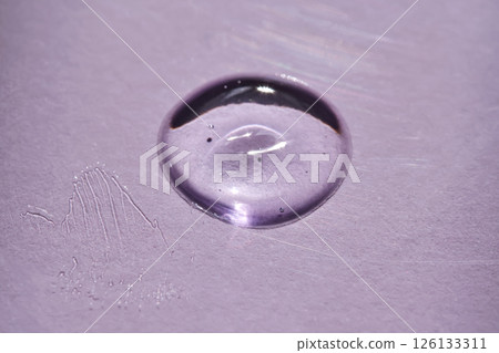 A drop of oil serum on a purple background with beautiful highlights. A drop of oil serum on a purple background with beautiful highlights. 126133311