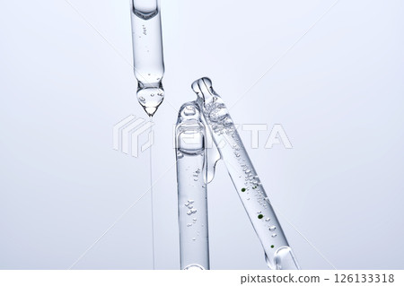 Three different face serum pipettes on a neutral background. 126133318
