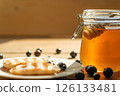 Pancakes Drizzled With Honey Beside a Jar on a Wooden Table, Sunlight Reflecting, Inviting Breakfast Scene for Cafes 126133481