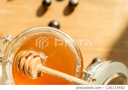 Golden Honey Drips From a Wooden Dipper, Bathed in Warm Sunlight symbolizing Wellness and a Delightful Dining Experience Golden Honey Drips From a Wooden Dipper, Bathed in Warm Sunlight symbolizing Wellness and a Delightful Dining Experience 126133482