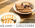 Breakfast Spread of Grilled Bread and Crisp Crackers on a Wooden Table, Bathed in Warm Sunlight perfect for Cafes and Food Blogs 126133484