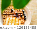 Whole Grain Crackers With Syrup and Blueberries on a Light Table, Highlighting Warmth and Texture for Food Blogs and Recipes 126133488