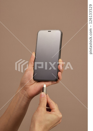 female hand connect charger cord into smartphone to charge battery, Wired charging 126133529