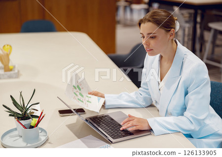 Professional Woman Conducting a Thorough Analysis of Data in a Modern Office Environment 126133905