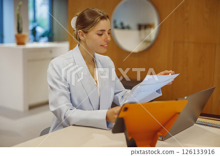 A Professional Woman is Engaged in Reviewing Important Documents in a Modern Workspace Setting A Professional Woman is Engaged in Reviewing Important Documents in a Modern Workspace Setting 126133916