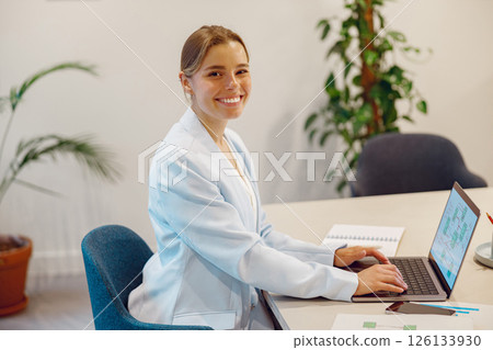 Smiling and Professional Individual in a Modern Office Setting with a Laptop in Front of them 126133930