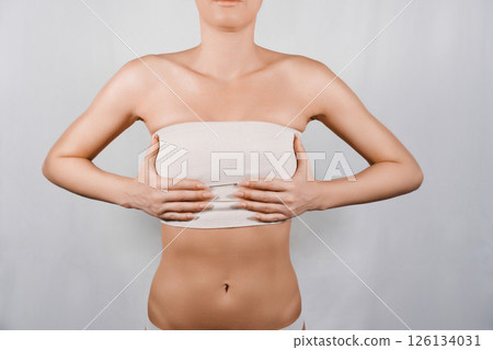 Breast reduction. Woman holding her breasts after plastic surgery with bandages Breast reduction. Woman holding her breasts after plastic surgery with bandages 126134031