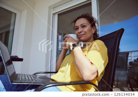 Woman Relaxing Outdoors With Laptop and Coffee in Casual Atmosphere 126134034