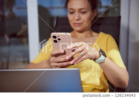 Woman Using Smartphone At Outdoor Setting While Multi-Tasking 126134043