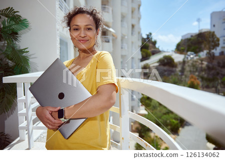 Confident Woman Holding Laptop Outdoors in Casual Setting Confident Woman Holding Laptop Outdoors in Casual Setting 126134062