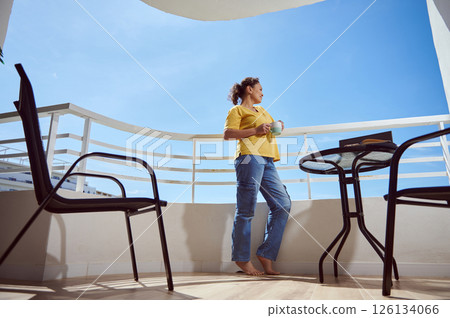 Woman Enjoying a Beverage While Relaxing On a Scenic Modern Balcony 126134066
