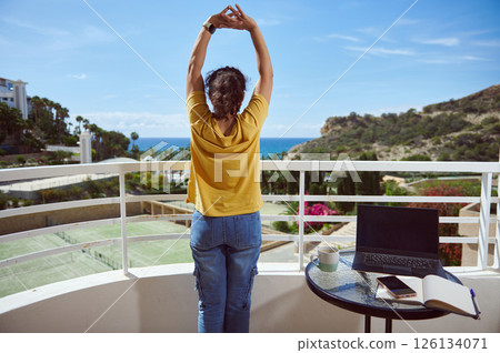 Woman Stretching on a Balcony with Scenic Ocean and Mountain View Woman Stretching on a Balcony with Scenic Ocean and Mountain View 126134071