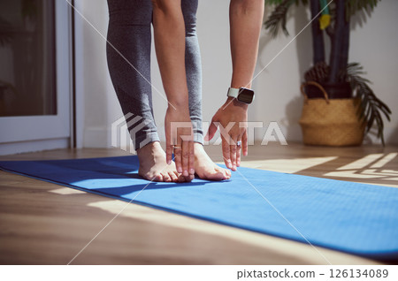 Person Performing Stretching Exercises on Blue Yoga Mat in Sunlit Room Person Performing Stretching Exercises on Blue Yoga Mat in Sunlit Room 126134089