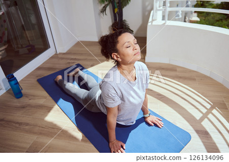 Focused Woman Practicing Yoga on a Sunny Balcony with Calm Ambiance Focused Woman Practicing Yoga on a Sunny Balcony with Calm Ambiance 126134096