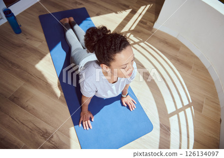 Woman Practicing Yoga Pose on Mat in Bright Naturally Lit Space 126134097