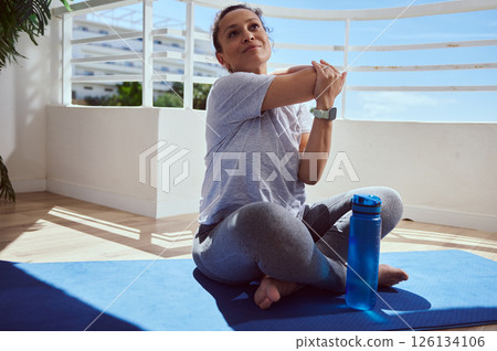 Woman Stretching on Yoga Mat During a Relaxing Workout Session 126134106