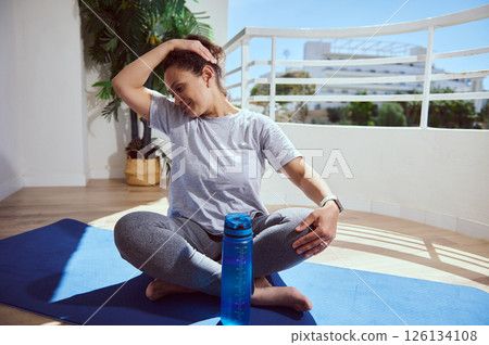 Young Woman Practicing Yoga on a Balcony With Sunny Outdoor Lighting 126134108