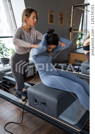 Woman doing rotation exercise on Pilates Reformer for the chest and back muscles, focusing on flexibility, strength, and control with determination Woman doing rotation exercise on Pilates Reformer for the chest and back muscles, focusing on flexibility, strength, and control with determination 126134161
