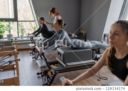 Womens doing Swan exercise on Pilates Reformer for the chest and back muscles, focusing on flexibility, strength, and control with determination Womens doing Swan exercise on Pilates Reformer for the chest and back muscles, focusing on flexibility, strength, and control with determination 126134174
