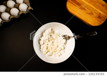 Process of making syrniki. Prepare cottage cheese for making dough. Top view on black surface. Russian cuisine. Process of making syrniki. Prepare cottage cheese for making dough. Top view on black surface. Russian cuisine. 126134191