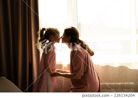 Close-up of mother and daughter exchanging loving whispers and giggles. Perfect illustration of secure attachment and childhood happiness. Close-up of mother and daughter exchanging loving whispers and giggles. Perfect illustration of secure attachment and childhood happiness. 126134204