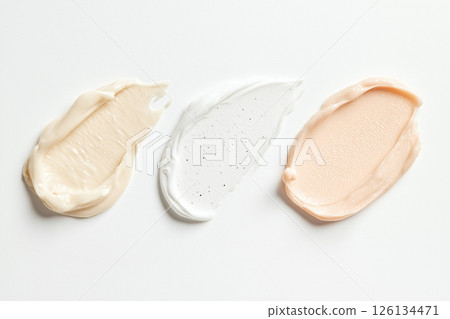 Three textured facial cream swatches in varying shades displayed on a white surface, ideal for representing beauty and skincare products. 126134471