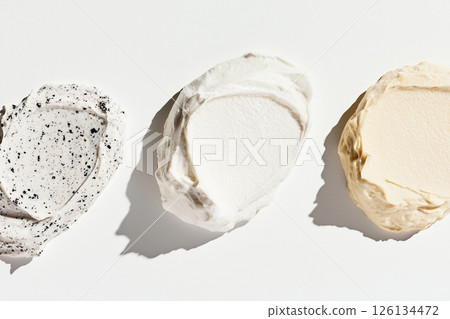 Three textured facial cream swatches in varying shades displayed on a white surface, ideal for representing beauty and skincare products. 126134472